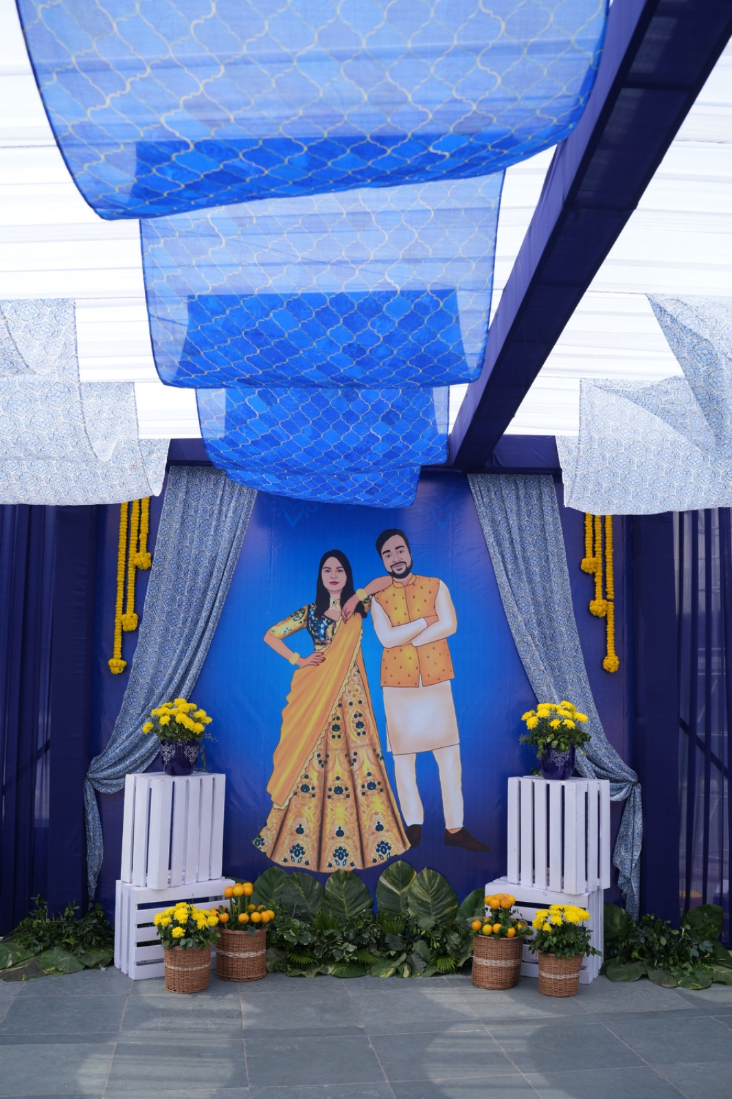 Blue portrait stage with patterned ceiling drapes, illustrated couple backdrop, and yellow florals