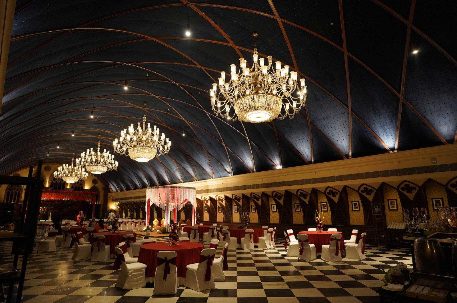 Ballroom with vaulted midnight ceiling, chandeliers, checkered floor, and formal dining layout